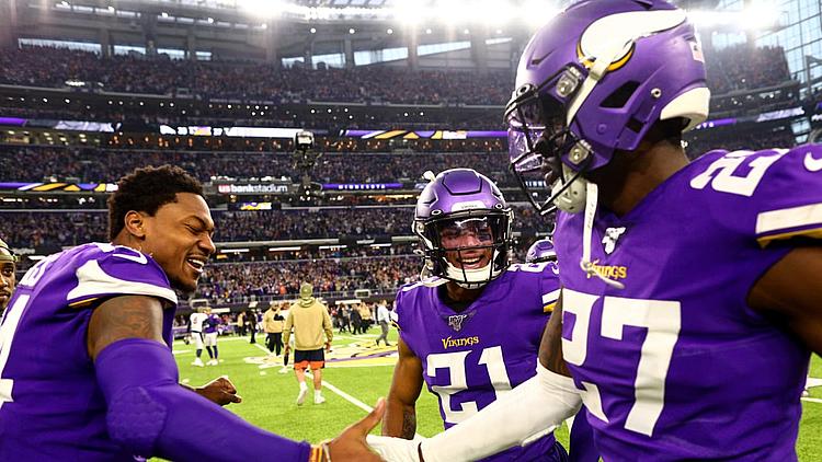 Minnesota Vikings players in purple jerseys celebrate on sideline during game.
