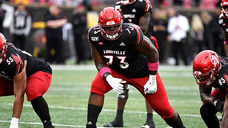 Louisville football player number 13 in defensive stance during game.