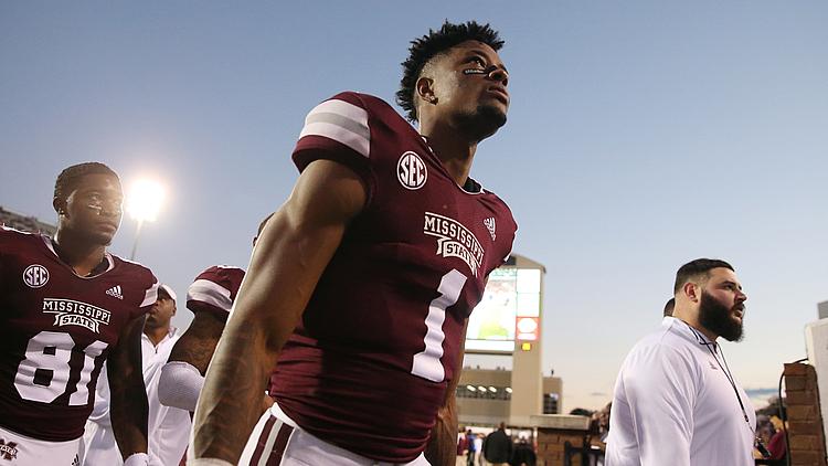 Mississippi State football player in maroon jersey during game with stadium visible.
