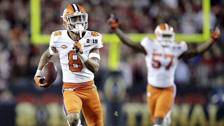 Football player in orange and white uniform running with ball during game.