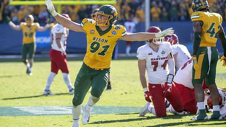 Football player in yellow jersey celebrates with arms raised during game.