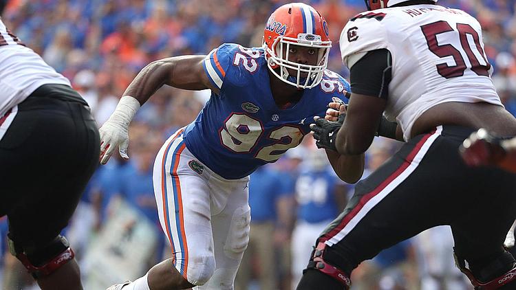 Florida Gators defensive player in blue jersey engaging opposing player in white jersey.