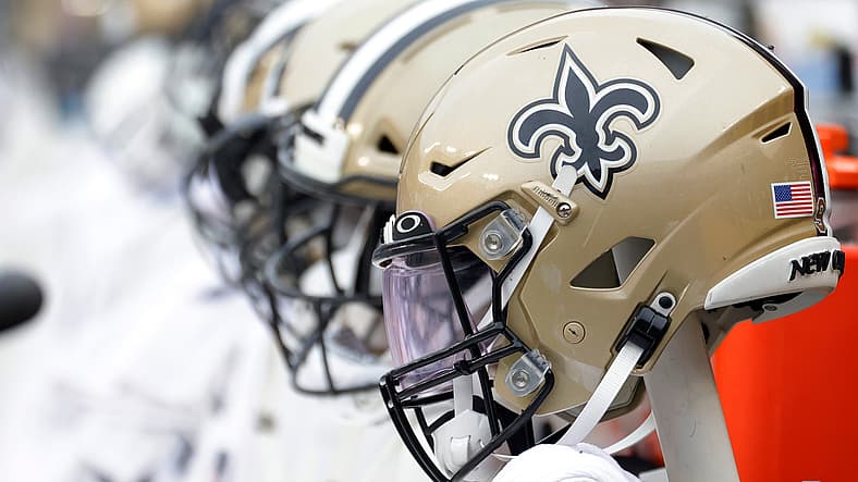 New Orleans Saints helmets lined up on the bench during a 2021 road game.