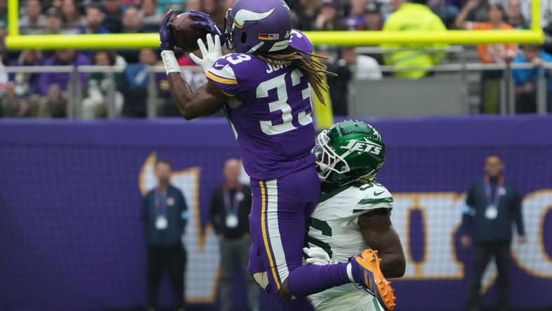 Aaron Jones catching a pass while Quincy Williams defends during a Vikings and Jets game in London.