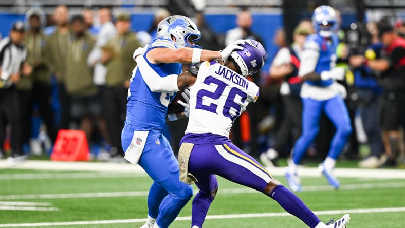 Lions tight end Sam LaPorta stiff-arms Vikings safety Theo Jackson during a game at Ford Field.