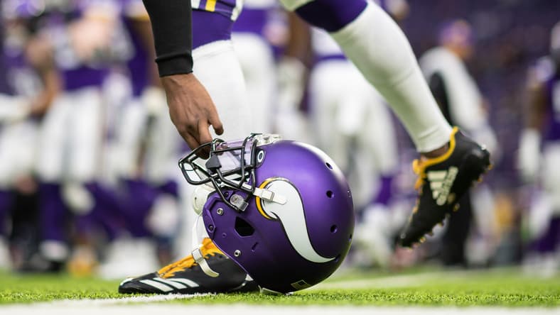 Mackensie Alexander bends down to pick up his helmet on the sideline before a Vikings game against the Bears.