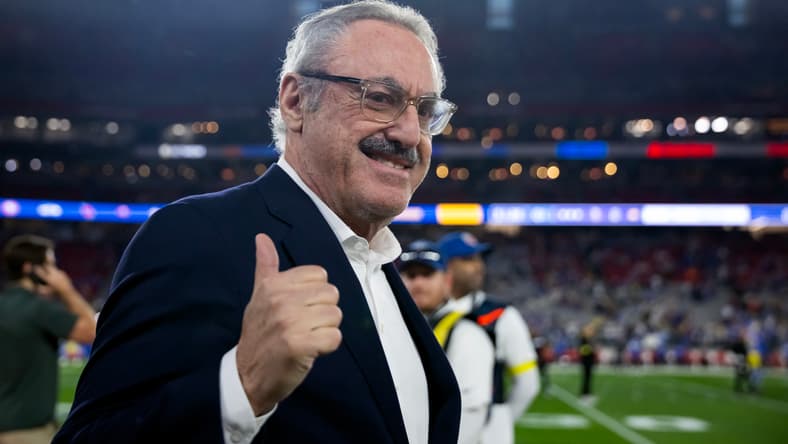 Vikings owner Zygi Wilf stands near the field before a playoff game against the Rams.