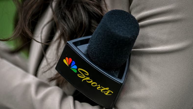 A Peacock sideline reporter holds a microphone in 2025