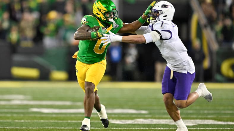 Oregon running back Jordon Davison stiff arms James Madison safety Jacob Thomas during a game at Autzen Stadium.