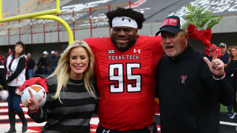 Jaylon Hutchings stands with Texas Tech head coach Joey McGuire and Debbie McGuire before a game.