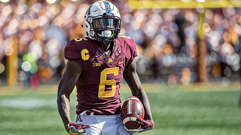 Football player wearing maroon number 6 jersey holds ball on field.