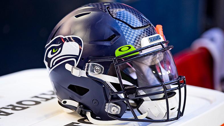 Seattle Seahawks football helmet displayed on white surface indoors.