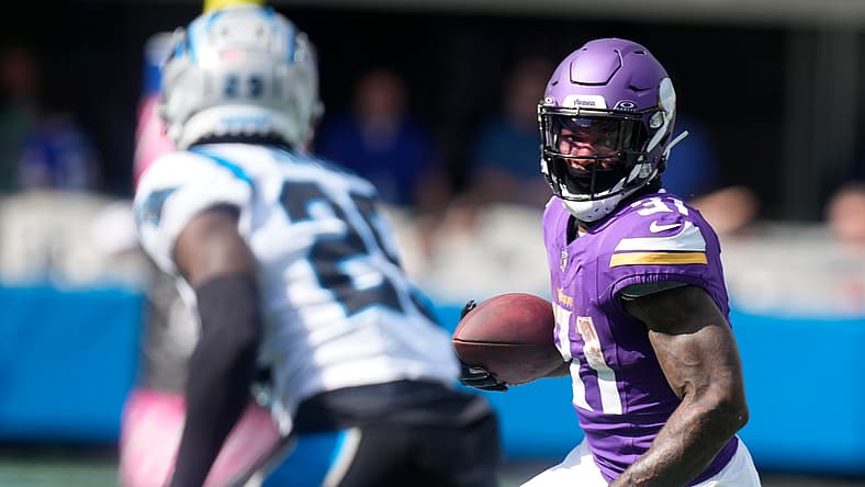 Cam Akers runs after a catch while defended by Xavier Woods against the Panthers in 2023.