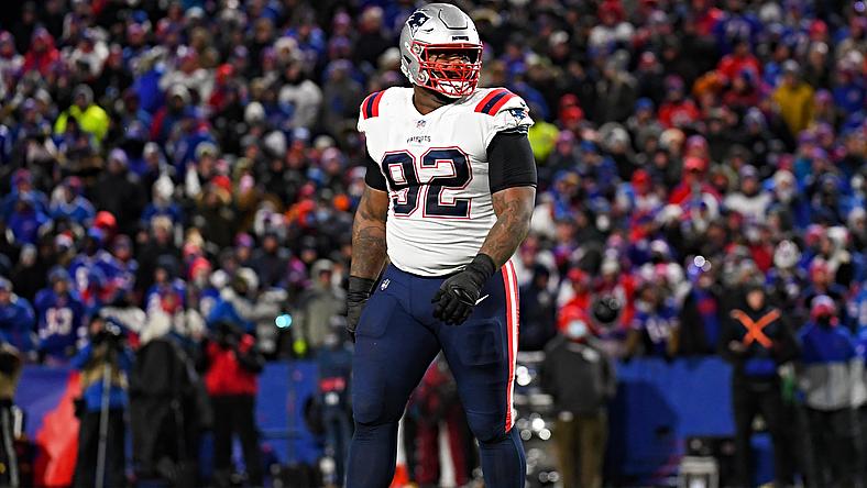 Football player wearing number 92 jersey stands on field during game with crowd.