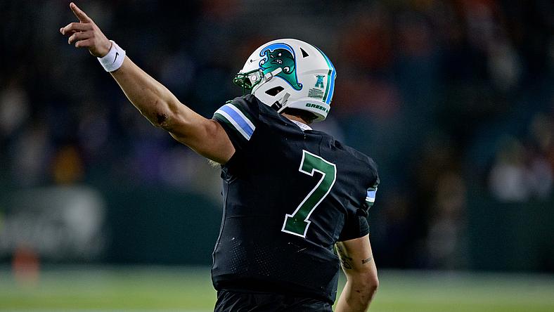 Football player wearing number 7 jersey pointing upward during game.