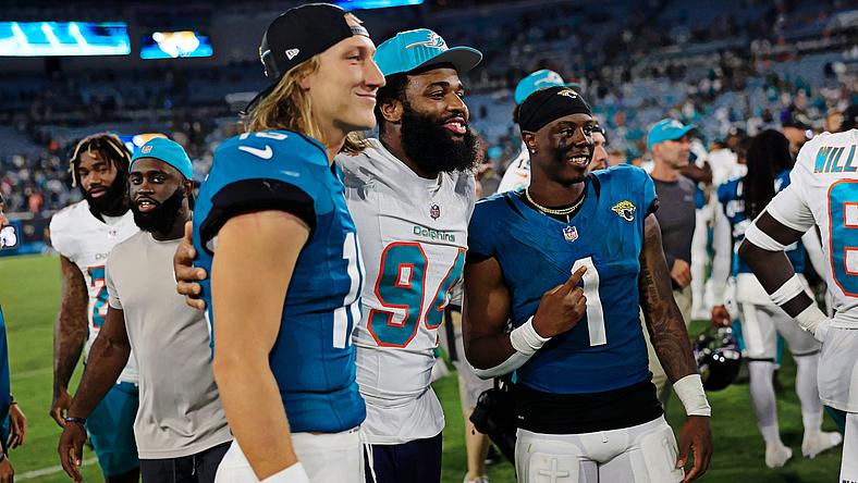 Football players in blue and white jerseys celebrate on field together.