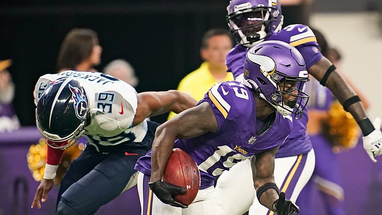 Vikings player in purple jersey catches football during game against Titans.