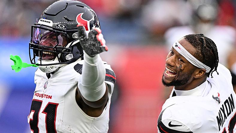 Houston Texans player pointing during NFL game, teammate celebrating beside.