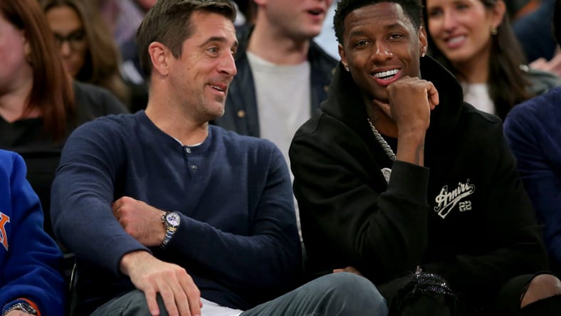 New York Jets quarterback Aaron Rodgers sits courtside with Sauce Gardner during an NBA playoff game.
