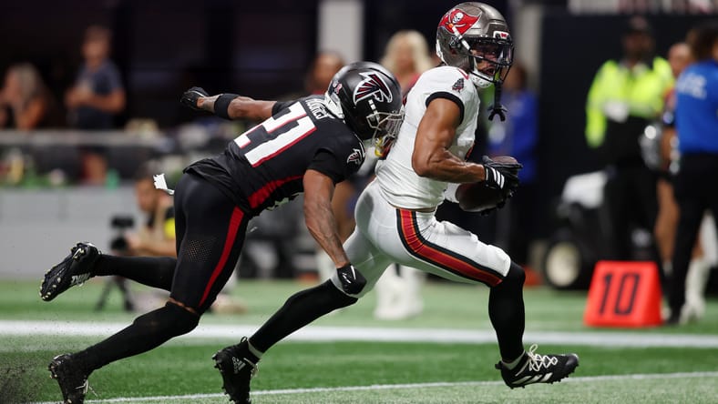 Emeka Egbuka scores a touchdown while defended by Mike Hughes at Mercedes-Benz Stadium.