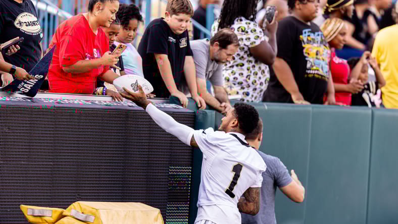 Alontae Taylor signs autographs for fans after a Saints training camp practice at Yulman Stadium.