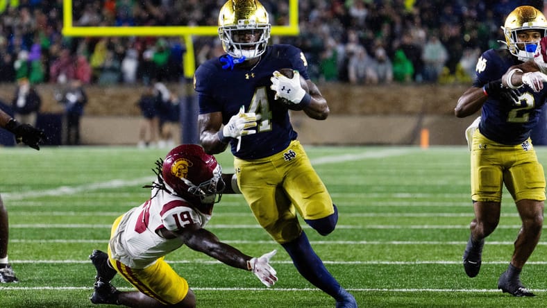 Notre Dame running back Jeremiyah Love rushing while a USC defender attempts a tackle. Vikings predictions 2026 NFL Draft.