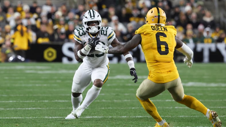 Emanuel Wilson runs as Patrick Queen closes in during Packers–Steelers action.