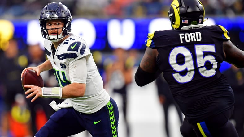 Sam Darnold rolls out as Poona Ford pursues during the Seahawks–Rams game.