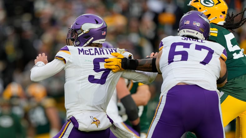 J.J. McCarthy pressured in the pocket by Packers defenders.