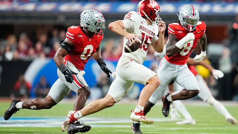 Indiana quarterback Fernando Mendoza scrambles past Ohio State defenders in Big Ten title game