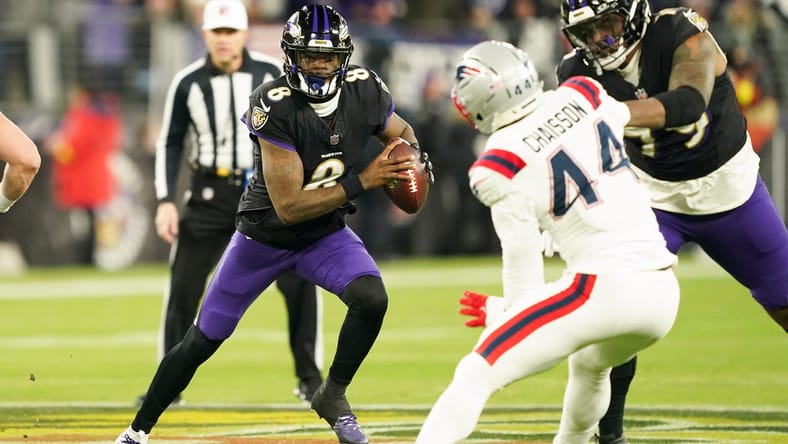 Lamar Jackson scrambles past a Patriots defender during a Ravens game.