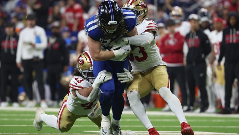 Eric Kendricks and Dee Winters tackle Tyler Warren during a 49ers-Colts game.