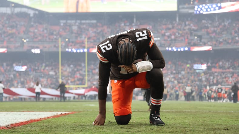 Shedeur Sanders kneels on the field during pregame warmups for the Browns.