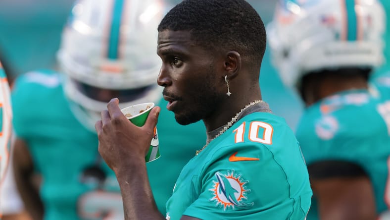 Tyreek Hill watching from the sideline during a Dolphins preseason game.