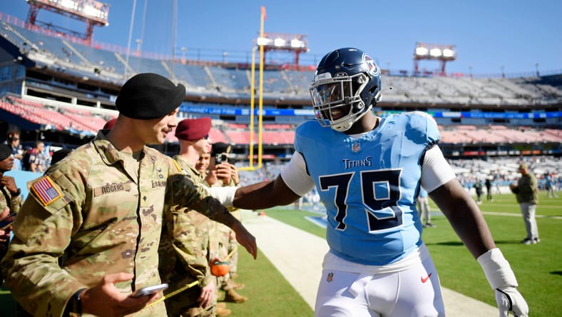 Lloyd Cushenberry III greets a military member on the field before a Titans game.