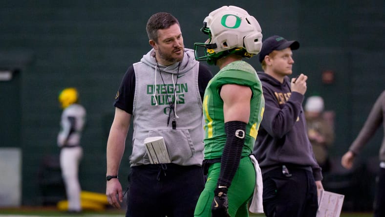 Oregon head coach Dan Lanning talks with defensive back Dillon Thieneman during bowl practice. Vikings draft pick prediction 2026. Vikings draft pick prediction 2026