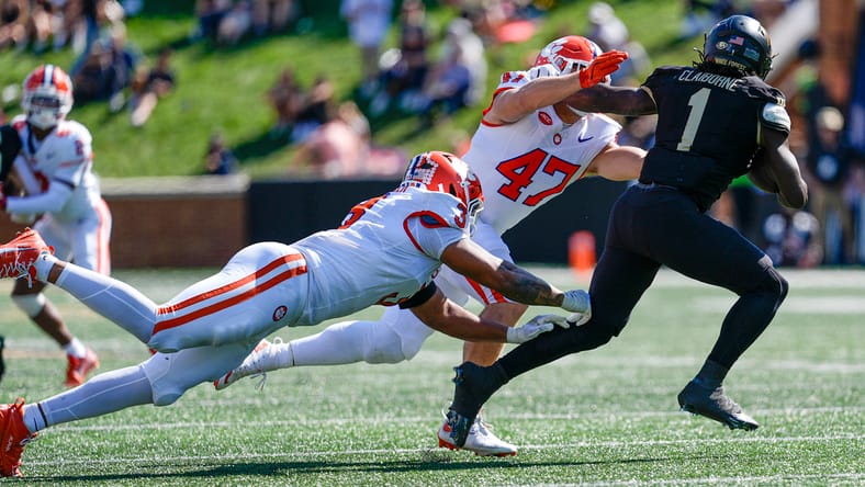 Demond Claiborne runs the ball while Clemson defenders attempt to tackle him during a game. Vikings draft grades