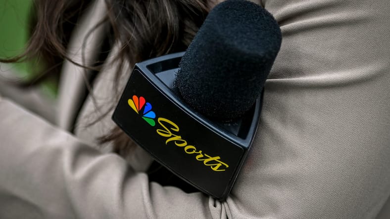 A Peacock sideline reporter holds a microphone in 2025