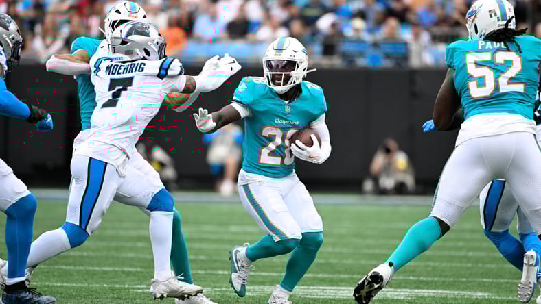 De'Von Achane running the ball while being pursued by a defender during a Dolphins game. De'Von Achane Vikings.