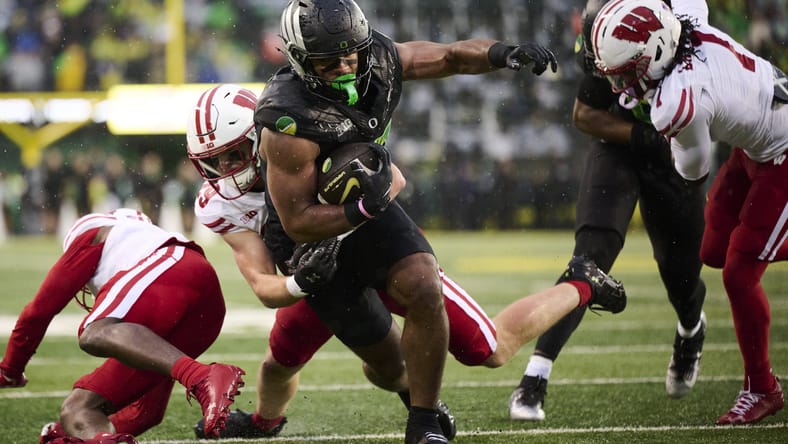 Kenyon Sadiq catches a pass while defended by a Wisconsin safety during a game. Vikings Round 1